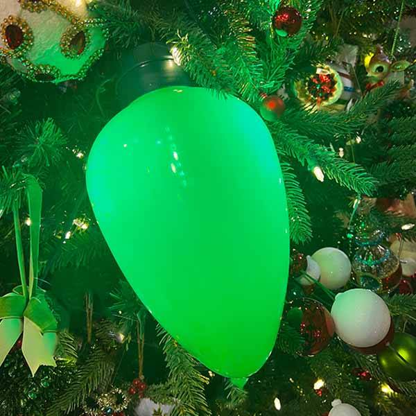 Jumbo green glowing retro-style Christmas bulb hanging on a Christmas tree at Hicks Nurseries.