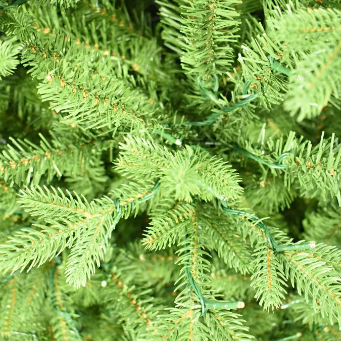 Close-up of lifelike Balsam Fir Multi-Function Lights 7.5 Ft. artificial Christmas tree branches interwoven with thin green wire string lights.