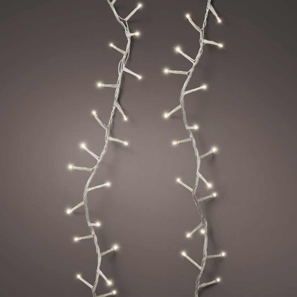 The LED 1000 ct. Compact String Lights Twinkle Warm White by Available for Pick-Up & Delivery emit a warm glow, with branch-like offshoots softly illuminating a plain, neutral gray background.