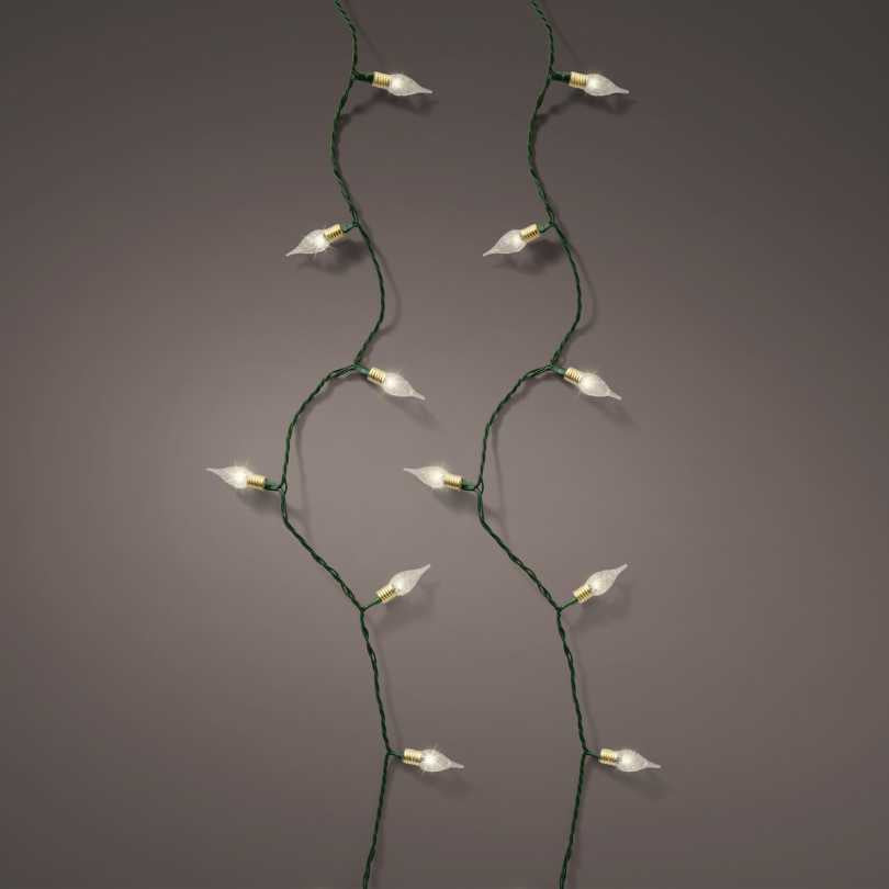 The LED 120 ct. Vintage String Lights Warm White by Available for Pick-Up & Delivery glow softly against a neutral gray backdrop, with evenly spaced bulbs hanging in gentle curves to create a cozy, inviting indoor atmosphere.