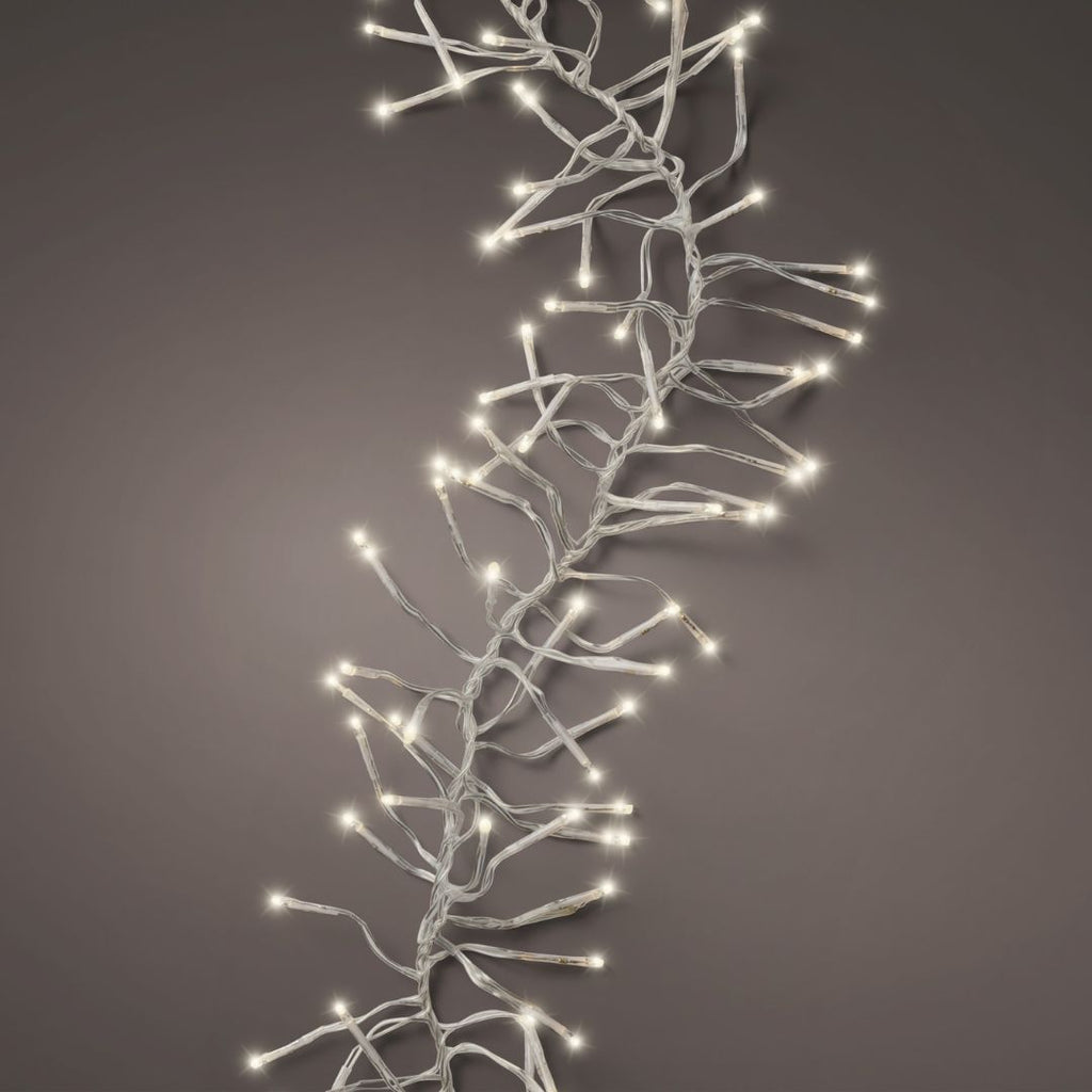 The Cluster LED 768 ct. String Lights Warm White by Available for Pickup & Delivery are elegantly draped across a neutral grey background, making them perfect for enhancing your holiday décor.