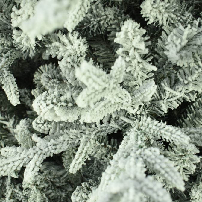 Close-up of artificial fir branches from a Nordic Flocked Fir Multi-Function Lights 9 Ft. tree, heavily covered in white flocking.