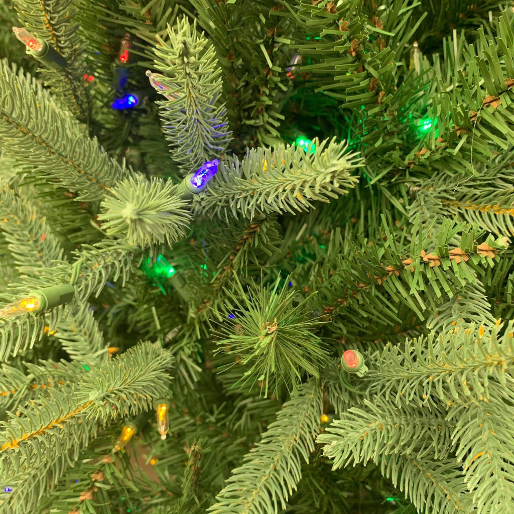 The Cranford Fir 7.5 Ft. tree, available for pick-up and delivery, features lifelike branches with colorful pre-lit LED lights in shades of blue, green, and yellow, showcasing intricate needle details that create a vibrant holiday atmosphere.