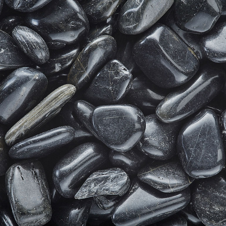 A close-up of Exotic Pebbles - Polished Black Pebble (5 lb.), featuring smooth, shiny black stones from Available for Pickup & Delivery, closely packed together and reflecting light.