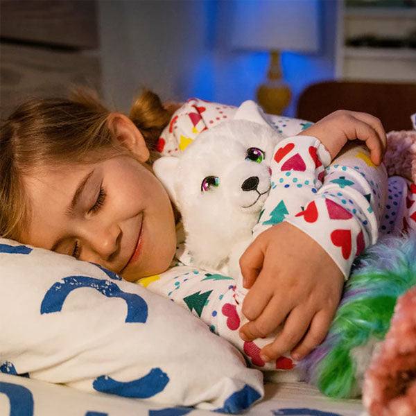 Plush Noorah from Elf on the Shelf. Photo shows a child sleeping while holding the stuffed annimal with a smile on her face.