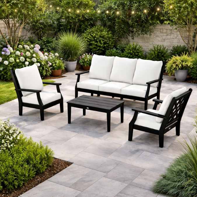 The Country Living by Polywood® Wovendale 6-Piece Outdoor Seating Set by Delivery Only features a sofa, two armchairs with white cushions, and a black coffee table—durable USA-made patio furniture perfect for lush, stylish outdoor spaces.