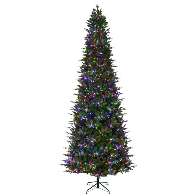 A slim Alberta Spruce Slim Multi-Function Lights 12 Ft. artificial Christmas tree decorated with multicolored string lights on a metal stand.