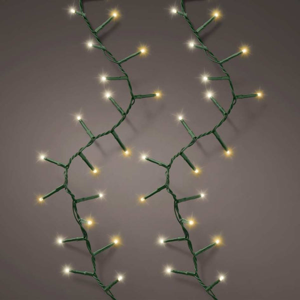 Two strands of Cluster LED 1128 ct. String Lights Warm White by Available for Pick-Up & Delivery hang vertically against a neutral gray background, featuring small glowing bulbs—perfect for holiday décor.
