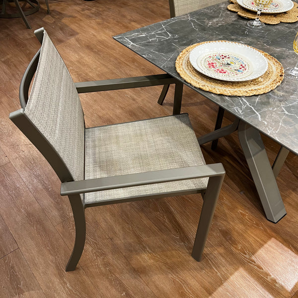 The Horizon Outdoor Patio Extension Dining Set by Delivery Only features a UV-resistant gray chair beside a rectangular table with a dark marbled top. Decorative plates on woven placemats and glassware complement its easy-to-clean surface, all set on warm-toned wooden floors.