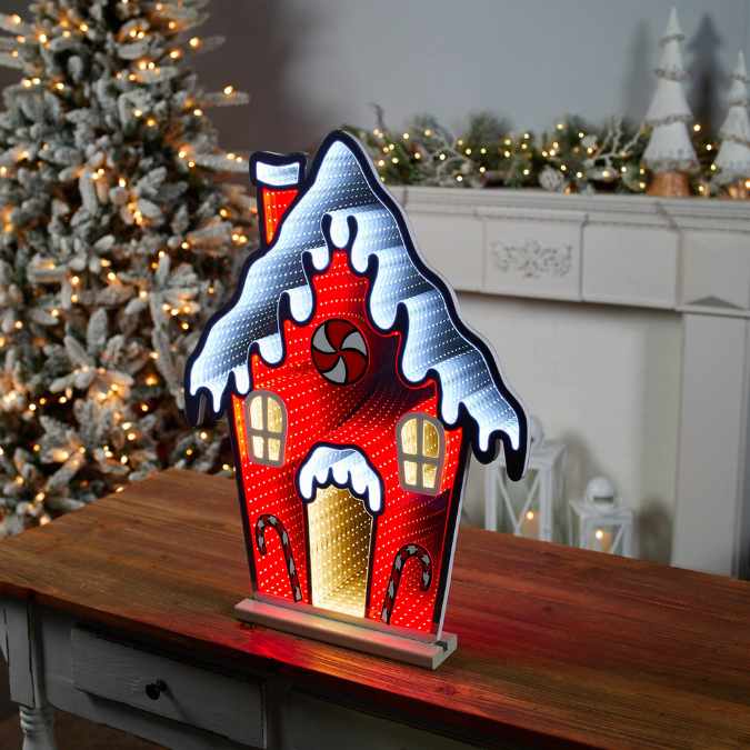 The Infinity Light – Gingerbread House - 26" from Available for Pick-Up & Delivery adds charm to your holiday décor, featuring a glowing, snow-covered roof that creates a cozy festive scene in any warmly lit room.