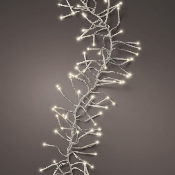 The Cluster LED 768 ct. String Lights Warm White by Available for Pickup & Delivery are elegantly draped across a neutral grey background, making them perfect for enhancing your holiday décor.