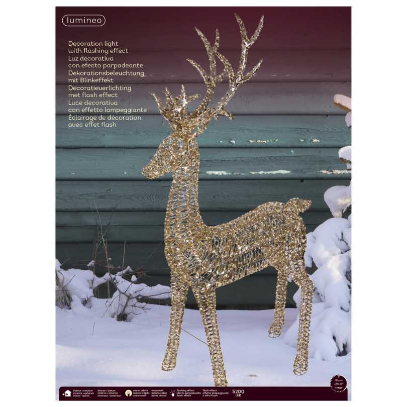 The Micro LED Grand Lit Reindeer – Warm White Lights from Available for Pick-Up & Delivery stands on snow before a blue wooden wall, with snow-covered bushes in the background and product information at the upper left.