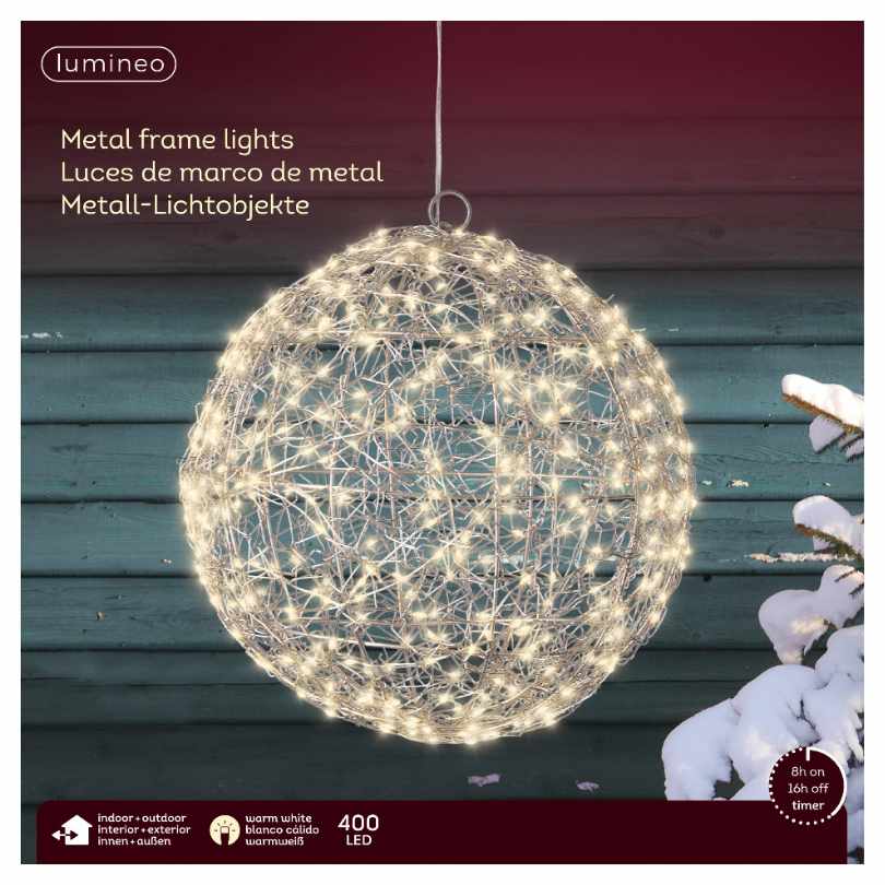 The 11-Inch Micro LED Lit Ball by Available for Pick-Up & Delivery features 400 warm white LEDs in a spherical metal design, hanging outdoors against a blue wooden wall with snow and white flowers at the bottom right.