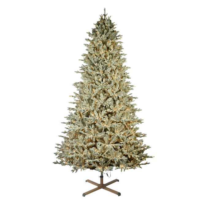 A 9 ft Nordic Flocked Fir Multi-Function Lights 9 Ft. artificial Christmas tree decorated with warm white lights, standing on a brown metal cross base.