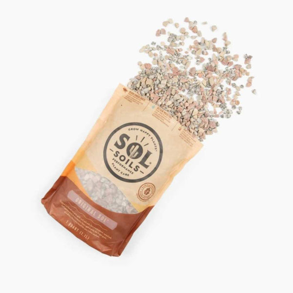 A partially opened Sol Soil - Topper Original Sol - 1 Qt. bag with small gravelly rocks, ideal as a decorative soil topper for potted plants, spills onto a white surface. The beige and brown bag shows the brand and is available for pick-up & delivery.