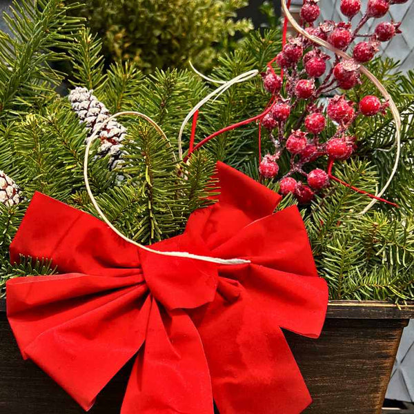 The Window Box - Mixed Greens by Available for Pick-Up & Delivery features fresh holiday greens, red berries, frosted pinecones, and a red fabric bow in a dark wooden box—perfect for outdoor window displays.