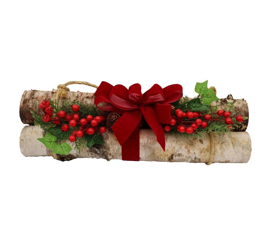 A bundle of two pieces of birch decorated for Christmas with a red bow, artificial berries and greens.