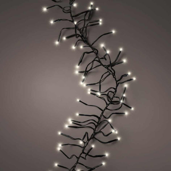 Cluster LED 768 ct. String Lights Warm White by Available for Pickup & Delivery are shown draped diagonally on a neutral grey background, featuring black wire and warm white bulbs—ideal for festive or holiday displays.