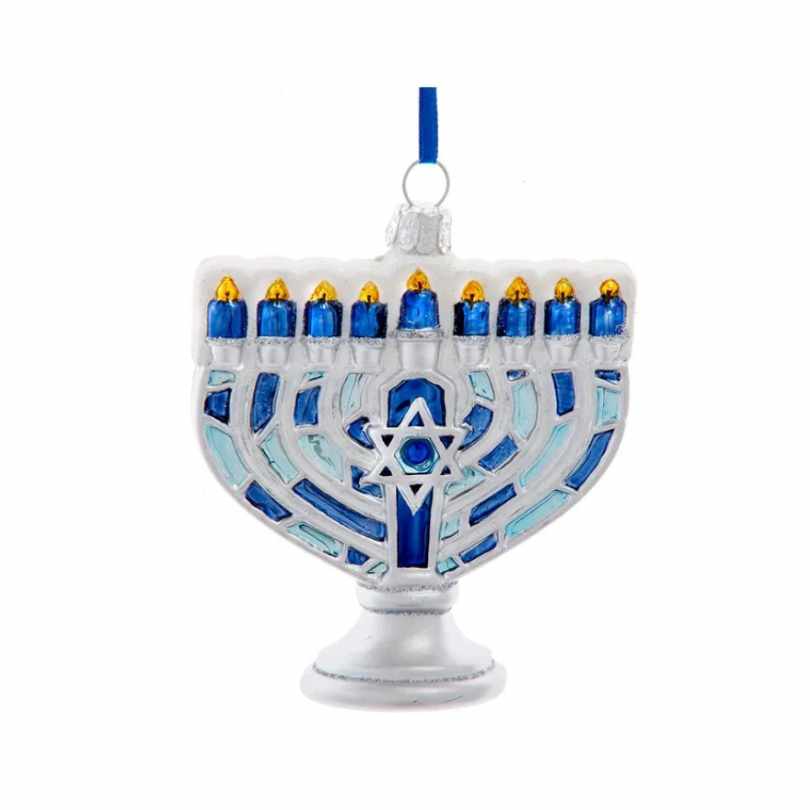 The Ornament - Glass Menorah by Available for Pick-Up & Delivery features nine blue candles, yellow flames, a blue Star of David, and hangs from a blue ribbon—a festive Hanukkah decoration for the Festival of Lights.