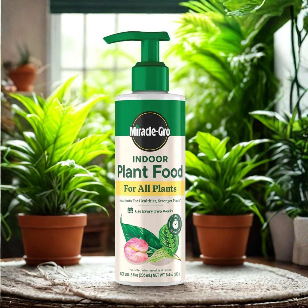 An 8oz. bottle of Miracle-Gro® Liquid Indoor Plant Food sits on a sunlit table, surrounded by vibrant potted houseplants with lush green leaves.