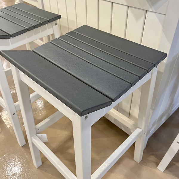 The Sunvilla Outdoor Patio Bar Set includes two white-framed stools with dark gray slatted seats on a shiny beige floor, set against a white paneled wall. From Delivery Only, they feature a simple, modern design, perfect for your patio or garden.
