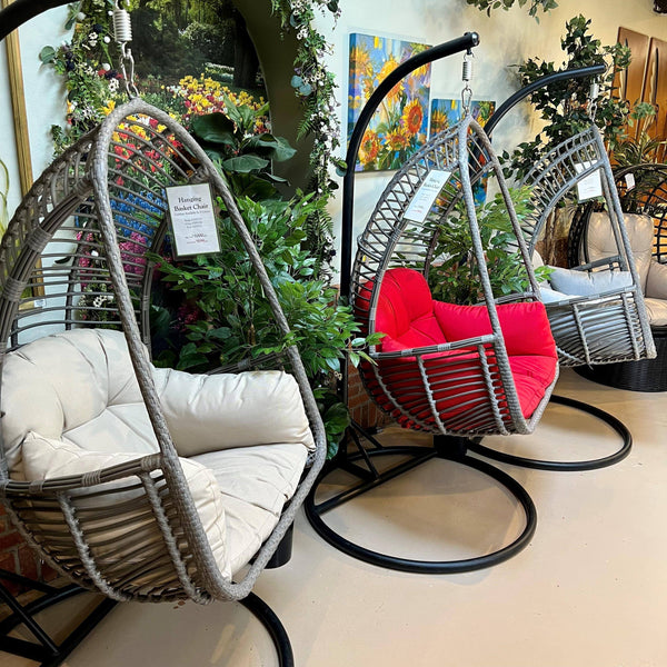 Three Pick-Up & Local Delivery Only Hanging Basket Chairs with durable metal frames and beige cushions are displayed indoors, surrounded by green plants and floral art—perfect for outdoor or indoor décor.